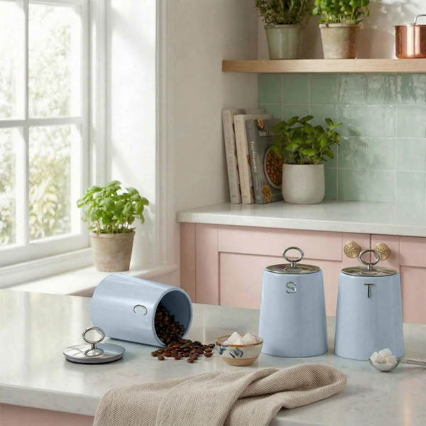 Set of three blue kitchen storage canisters with lettered lids on a worktop