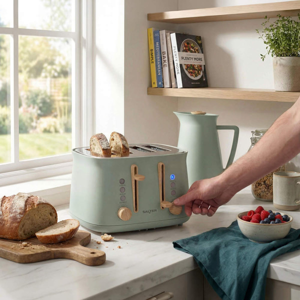 Pastel green four-slot toaster with bread, shown in a modern kitchen setting.