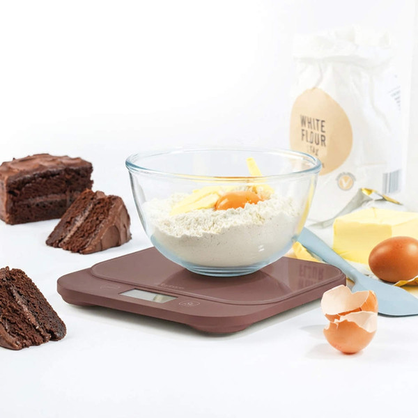 Brown digital kitchen scale with baking ingredients and chocolate cake slices