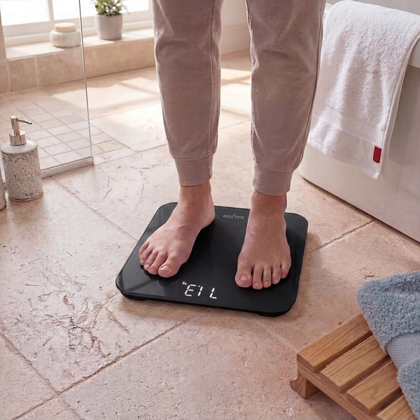 Black digital bathroom scale with feet, showing weight reading