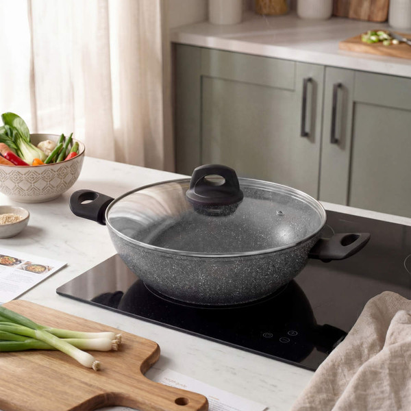 Grey non-stick casserole dish with glass lid on hob in modern kitchen