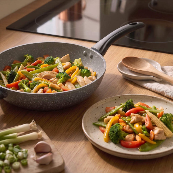 Non-stick frying pan cooking colourful vegetable stir-fry on induction hob in modern UK kitchen