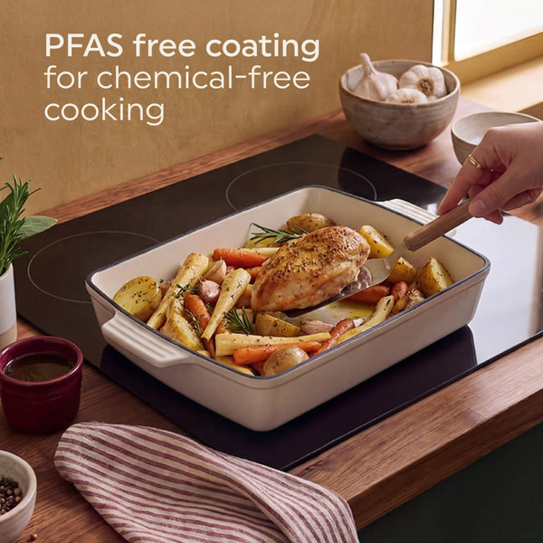 Cream ceramic roasting dish with sausages, potatoes and root vegetables on wooden board