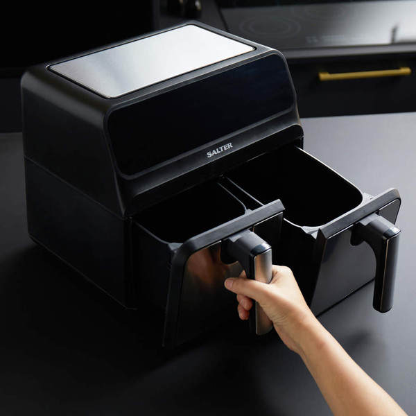 Black double drawer air fryer with hand opening left basket, kitchen counter background