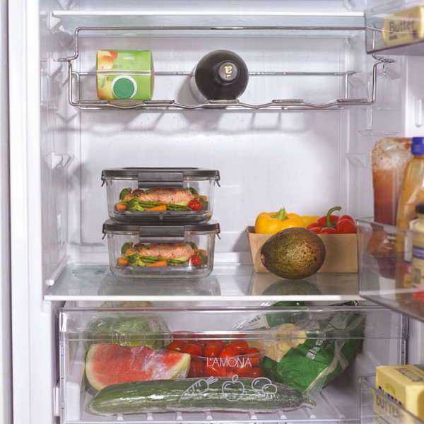 Stacked glass food containers in fridge with fresh salmon, vegetables and salad