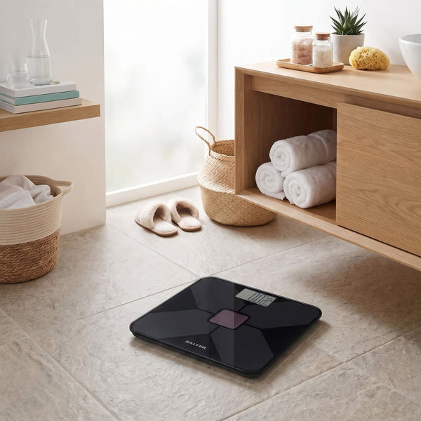 Black digital bathroom scale on tiled floor, shown in modern bathroom setting