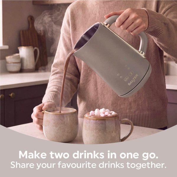Grey kettle pouring hot chocolate into two mugs