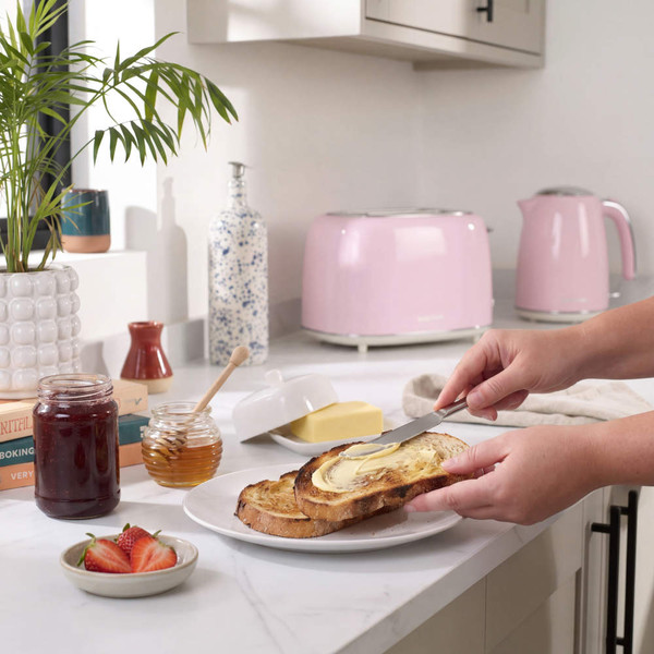 Pink toaster and kettle on kitchen counter, morning breakfast scene with toast, butter, and spreads
