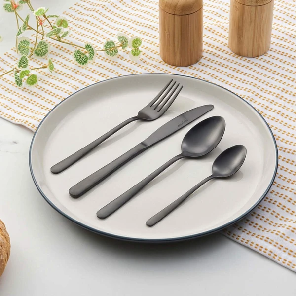 Set of matte black cutlery arranged on white plate