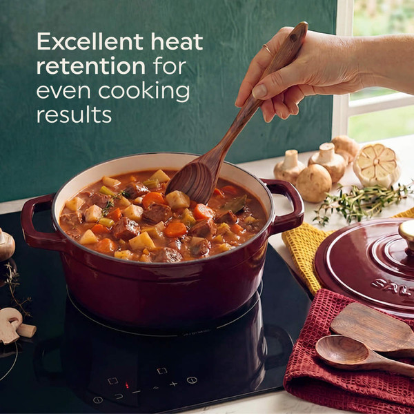 Red cast iron casserole dish with oven mitts, holding baked vegetable gratin on kitchen counter