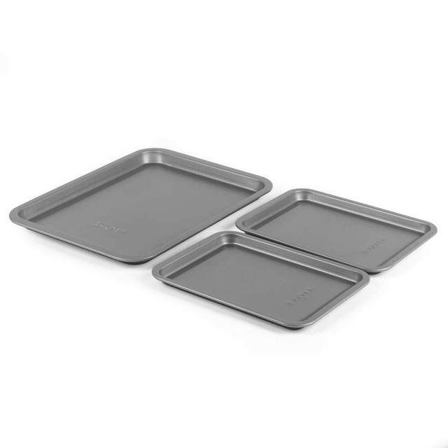 Set of three grey non-stick baking trays, shown stacked on white background