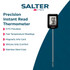 Digital meat thermometer measuring temperature in cooked steak on wooden board