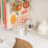 Clear acrylic salt and pepper mills on a kitchen counter in front of cookbooks