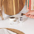 Bowl of grilled chicken salad with vegetables on dining table, hand using salt grinder