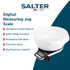Digital kitchen scale with white mixing bowl, flour and baking tools on worktop