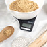 Digital kitchen scale weighing brown sugar in white mixing bowl