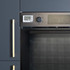 Built-in oven in matte black kitchen with brass handles, timer visible