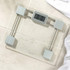 Silver digital bathroom scale with glass platform on tiled floor