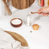 Clear acrylic salt mill being filled from wooden bowl with sea salt