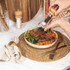 Hand grinding black pepper onto steak salad in bowl, for kitchenware product listing.