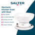 White mechanical kitchen scale with bowl on worktop, surrounded by baking items