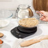Digital kitchen scale with mixing bowl measuring brown sugar on kitchen worktop
