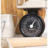 Black Salter mechanical kitchen scale in drawer beside wooden utensils