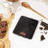 Black digital kitchen scale on counter with brownies, jug of milk and chocolate pieces