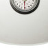 Mechanical bathroom scale with textured white surface, close-up of dial display