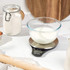 Glass bowl of milk on Salter digital kitchen scale, baking ingredients nearby