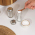 Glass salt and pepper shakers with metal lids, one being filled with ground pepper