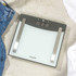 Salter glass bathroom scale with stainless steel accents on tiled floor