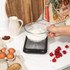 Digital kitchen scale with stainless steel platform and black display, showing zero.
