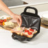 Black geometric Salter sandwich maker with rose gold detail, shown beside plate of toasted sandwiches.
