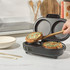 Mini omelette maker with two cooked omelettes, one being lifted out with wooden tongs