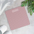 Pink digital bathroom scale with textured surface, on tiled floor with slippers and plant nearby