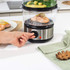 Electric food steamer with three clear tiers and silver base stored in kitchen cupboard