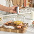 Hand using silver electric whisk to beat eggs in glass bowl on kitchen counter
