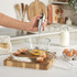 Hand using silver electric whisk to beat eggs in glass bowl on kitchen counter