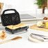 Sandwich toaster with toasted sandwiches being lifted out using a wooden spatula