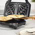 Sandwich toaster with toasted sandwiches being lifted out using a wooden spatula
