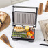 Grey electric grill surface with fat collection tray, close-up showing textured non-stick coating