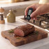 Digital food thermometer checking cake in round tin on kitchen worktop