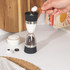 Dual salt and pepper grinder with black and stainless steel finish, shown on kitchen counter.
