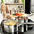 Stainless steel saucepan with tomato sauce on induction hob, fresh tomatoes in background