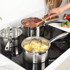 Set of three silver stainless steel saucepans, stacked with lid, shown from side