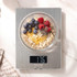 Slim silver digital kitchen scale in a drawer beside wooden utensils