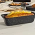 Grey speckled loaf tin with lemon drizzle cake on kitchen worktop