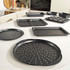 Set of black speckled non-stick bakeware trays and tins on a kitchen counter