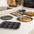 Non-stick black bakeware set shown with pizza, muffins, cookies, and roasted vegetables.